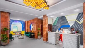 A modern lobby with a reception desk, green seating area, and decorative wall art. - Deluxe Room Near Burj Khalifa Metro By E R (Dubai)