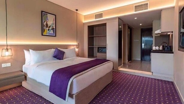 A modern hotel room with a large bed, a walk-in closet, and a kitchenette. - Deluxe Room Near Burj Khalifa Metro By E R (Dubai)