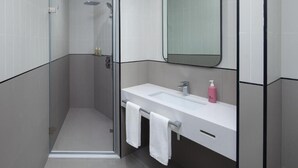 A modern bathroom with a glass-enclosed shower, a white sink with a mirror, and a towel rack. - King Room Near Expo 2020 by ER (Dubai)