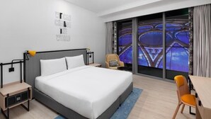 A modern hotel room with a large bed, a desk, and a chair. There is a large window with a view of a structure outside. - King Room Near Expo 2020 by ER (Dubai)