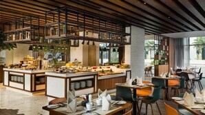 A modern restaurant with a central bar area, multiple dining tables, and a high ceiling with exposed beams. - Two Bedroom Apartment Near Moe By E R (Dubai)