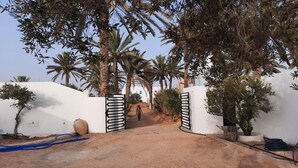 A gated entrance with palm trees and a clear sky. - Maison D'hote Saida Djerba Houmt Souk (Sedghiane)