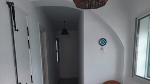 A hallway with a wicker ceiling light, a wooden chair, a small table, and a target decoration on the wall. - Maison D'hote Saida Djerba Houmt Souk (Sedghiane)