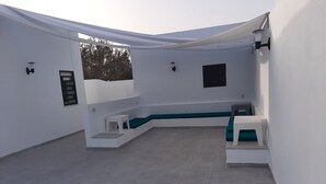 A covered outdoor area with a seating arrangement, including a bench and a small table. - Maison D'hote Saida Djerba Houmt Souk (Sedghiane)