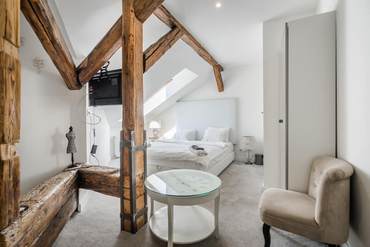 Ein Schlafzimmer mit einer Schlafgalerie, einem Bett, einem Sessel und einem kleinen Tisch.