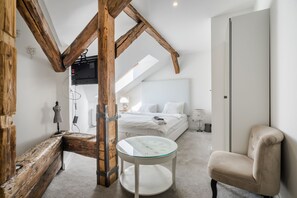 A bedroom with a loft-style ceiling, a bed, a chair, and a small table. - Nador Boutique Best Location By BQA (Budapest)