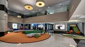 A spacious lobby with a central seating area, a staircase, and a reception desk. - Standard Room Near Sharjah Expo Centre By E R (Sharjah)