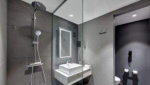 A modern bathroom with a glass-enclosed shower, a white sink, and a toilet. - Standard Room Near Sharjah Expo Centre By E R (Sharjah)