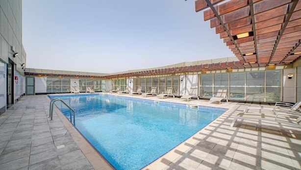 Une piscine intérieure à l’eau d’un bleu cristallin, entourée de chaises longues et d’un espace abrité doté d’un plafond en bois.