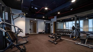 Une salle de sport équipée de divers appareils d’exercice, notamment des machines de musculation et des haltères.