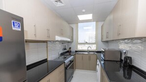 Une cuisine moderne avec des meubles de couleur beige, un réfrigérateur en acier inoxydable, une cuisinière à gaz et un four à micro-ondes.