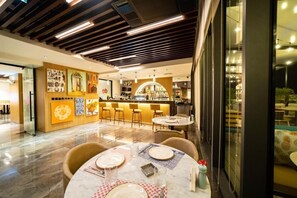 Ein modernes Restaurant mit Barbereich, Marmorböden und einem Essbereich mit Tischen für zwei Personen.