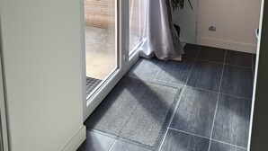 Una habitación con puerta corrediza de vidrio que da a un espacio exterior, un reloj de pared, un certificado enmarcado y una planta en maceta.