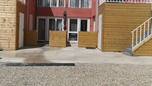 Un edificio de varios pisos con fachada roja, balcones de madera y un patio de grava.