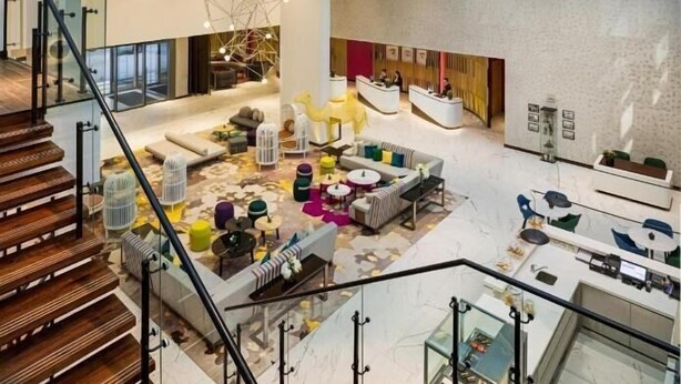 A spacious lobby with a high ceiling, modern furniture, and a staircase leading to upper levels. - One Bedroom Apartment Near Moe By E R (Dubai)