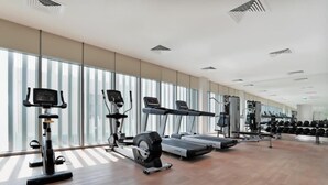 Et moderne fitnesscenter med løbebånd, styrketræningsudstyr og en stor spejlvæg.