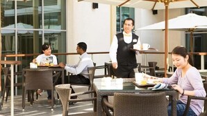 An outdoor café with wicker furniture and white umbrellas. - Standard Room Near Port Saeed Plaza By E R (Dubai)