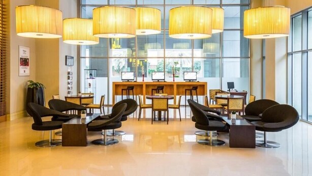 A modern lobby with a reception desk, multiple seating areas, and large windows offering a view of the outdoors. - Standard Room Near Port Saeed Plaza By E R (Dubai)