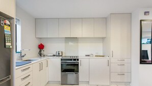 A modern kitchen with white cabinetry, a built-in oven, and a stainless steel refrigerator. - Stunning 2BR in Kelston with WIFI and Carpark (Auckland West)
