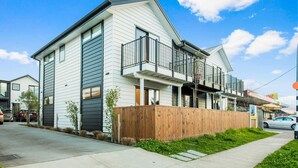 A modern two-story house with a balcony and a wooden fence. - Stunning 2BR in Kelston with WIFI and Carpark (Auckland West)