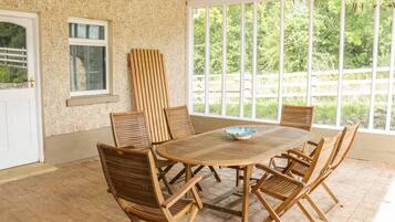Relax in this serene patio area with a round table and six chairs, surrounded by a beautiful wooded view.