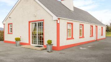 Stylish single-story building with a pitched roof and chimney, featuring red-framed windows and a white door.