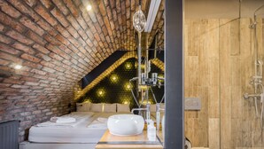 A modern bedroom with a large bed, a wooden bedside table, a white basin, and a brick ceiling. - Butik Apartments by BQA (Budapest)