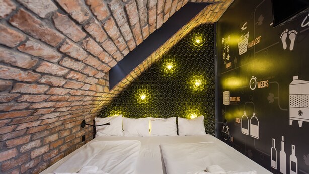 A room with a brick wall, two beds, and a wall with icons and text. - Butik Apartments by BQA (Budapest)