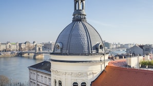 A building with a dome and a red-tiled roof, overlooking a river and a bridge. - Butik Apartments by BQA (Budapest)