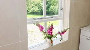 A bathroom with a window, a white toilet, and a vase with flowers on the windowsill. - THE OLD WHITE COTTAGE, pet friendly in Shillelagh, County Wicklow (Shillelagh)