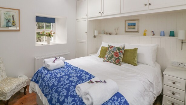 A bedroom with a bed, a window, a bedside table, and a wardrobe. - THE OLD WHITE COTTAGE, pet friendly in Shillelagh, County Wicklow (Shillelagh)