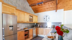 A modern kitchen with wooden cabinets, a stainless steel refrigerator, a microwave, and a sink.