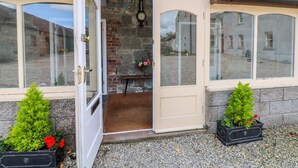 A traditional house with a wooden facade, a stone wall, and a door leading to a small porch area.