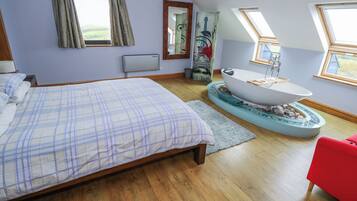 A bedroom with a bed, a bathtub, and a red chair.