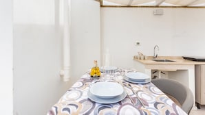 A kitchen with a sink, a table set for two with plates, a bottle, and a vase. - 3471 Lecasinedico` - Linda Lucia by Barbarhouse (Castrignano del Capo)