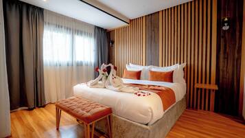 A modern bedroom with a large bed, wooden panel wall, and a bench.