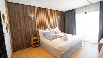 Un dormitorio moderno con una pared de acento de madera, una cama grande con cubrecama blanco, una mesita de noche y una lámpara de noche.