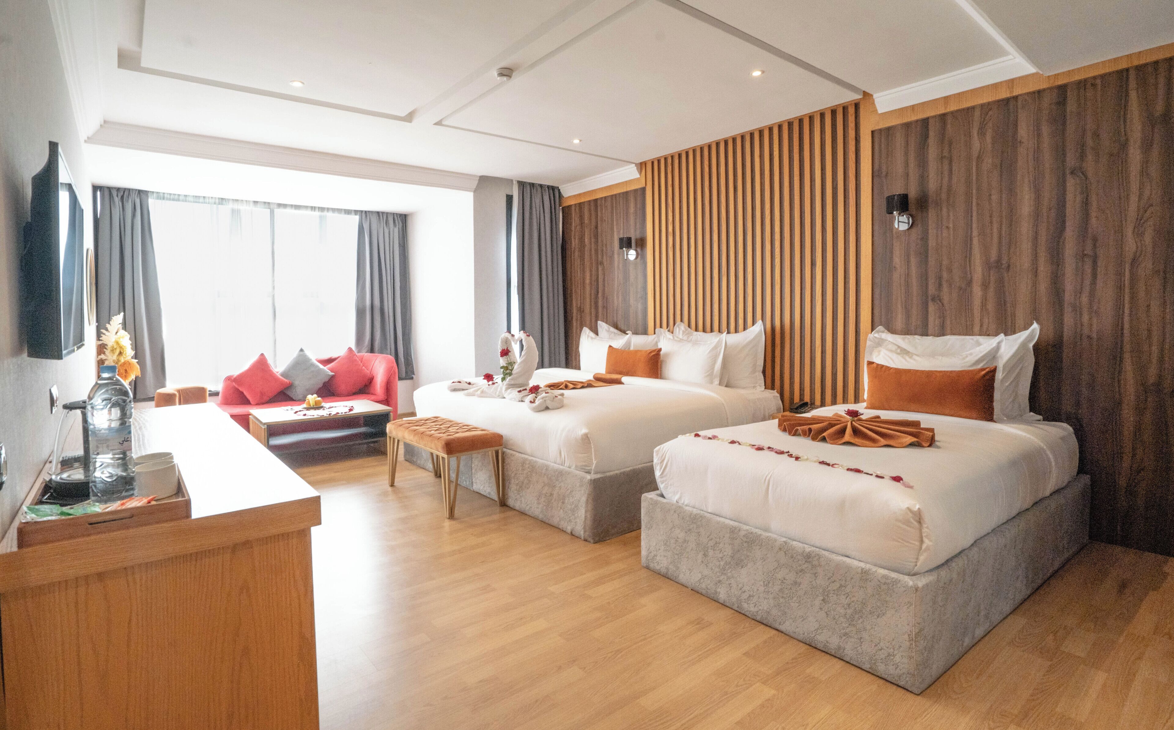 Une chambre d’hôtel moderne avec deux lits, un canapé, un bureau et une grande fenêtre.