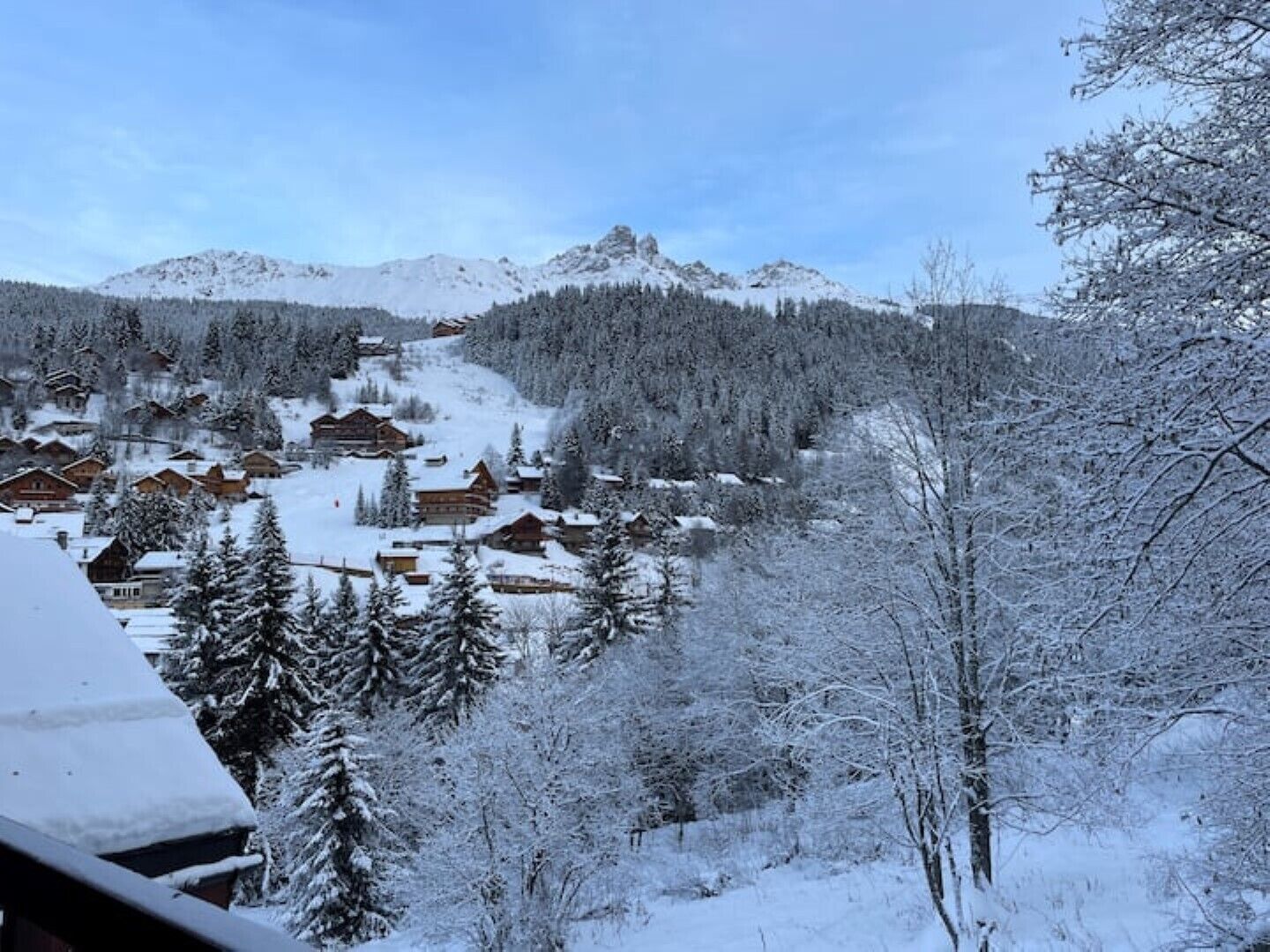 A snow-covered mountain village with wooden cabins and a forested backdrop.