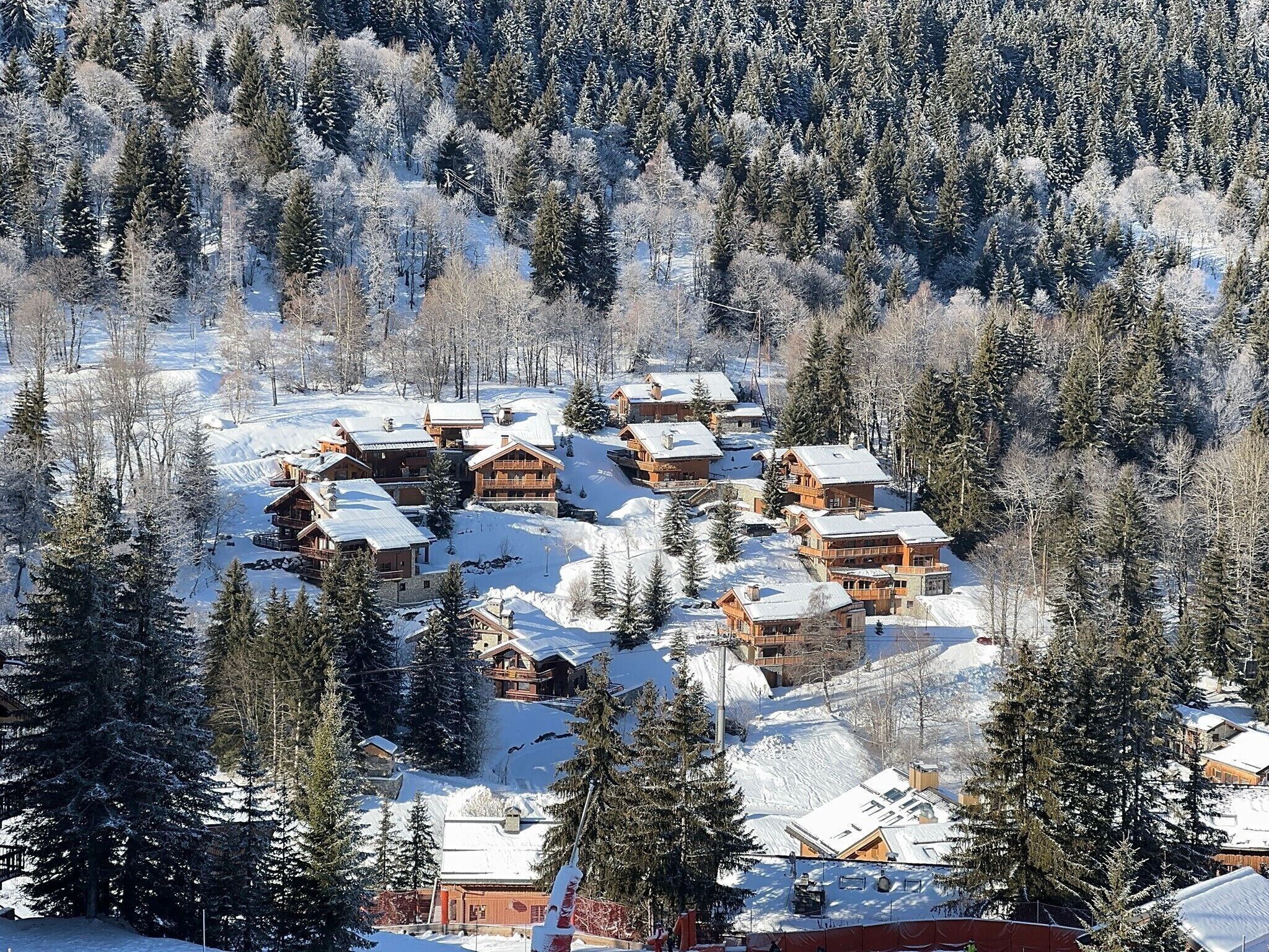 A snow-covered lodge with multiple wooden cabins surrounded by dense evergreen trees.