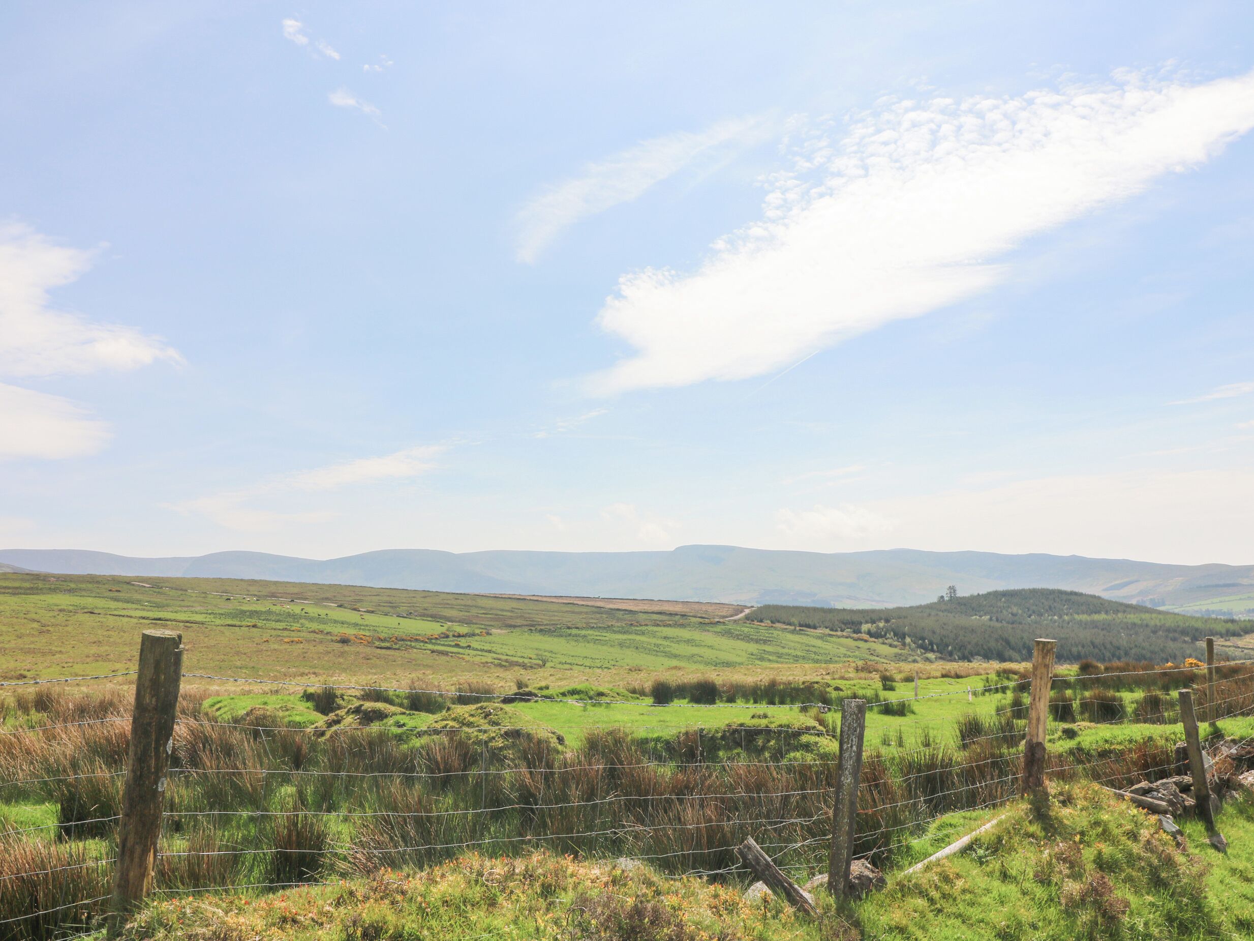 Un paysage rural caractérisé par des collines douces et un ciel dégagé.