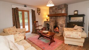 A cozy living room with a stone fireplace, two sofas, a wooden table, and a red rug.
