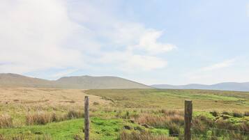 A rural landscape with a grassy field, a wooden fence, and distant hills.