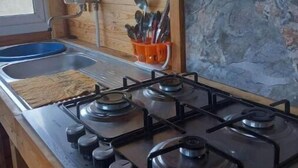 Una cocina con estufa a gas, un lavamanos y armarios de madera.
