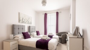 A modern hotel room with two beds, a desk, and a chair. - 1 Bedroom Luxury Apartment in Redhill (Redhill)