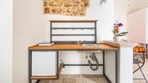 A compact kitchen with a stone wall, a wooden countertop, a built-in sink, and a small refrigerator. - 3396 Leucadense - Grotta 1 by Barbarhouse (Castrignano del Capo)
