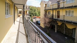 Un bâtiment jaune doté de balcons, d’une galerie couverte et d’un espace de stationnement.