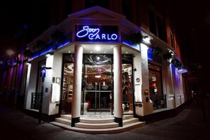 A storefront with a neon sign reading "San Carlo" and an "Open All Day" sign.