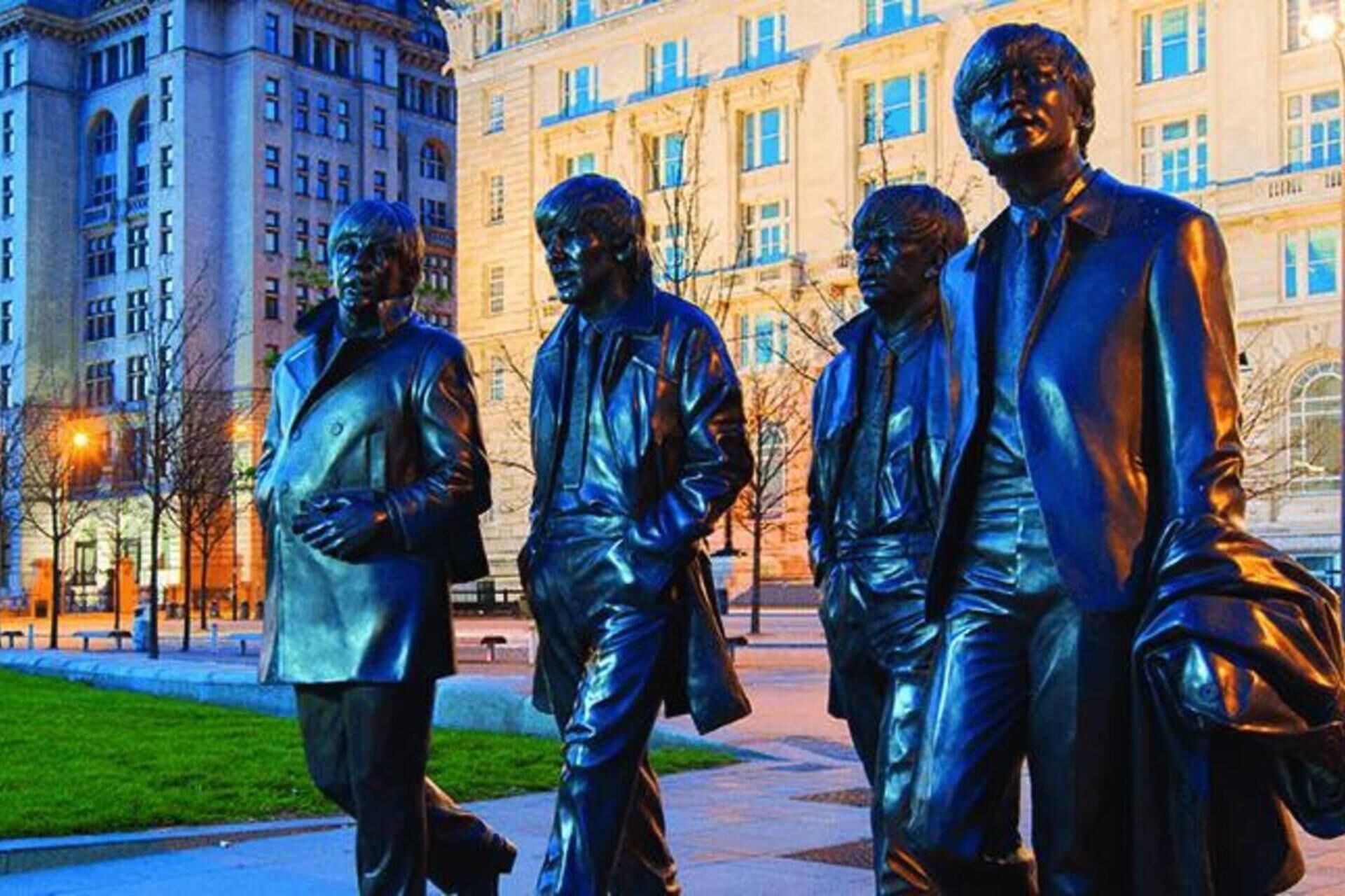 A group of bronze statues in a city square.