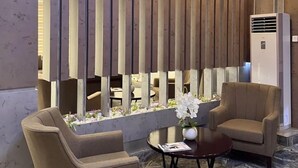Eine moderne Lobby mit Sitzgelegenheiten, einer dekorativen Holzvertäfelung und einem Marmorboden.